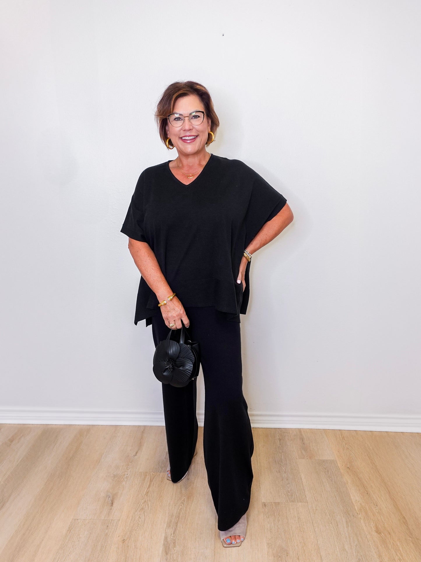 Woman wearing a black outfit standing against a white wall.