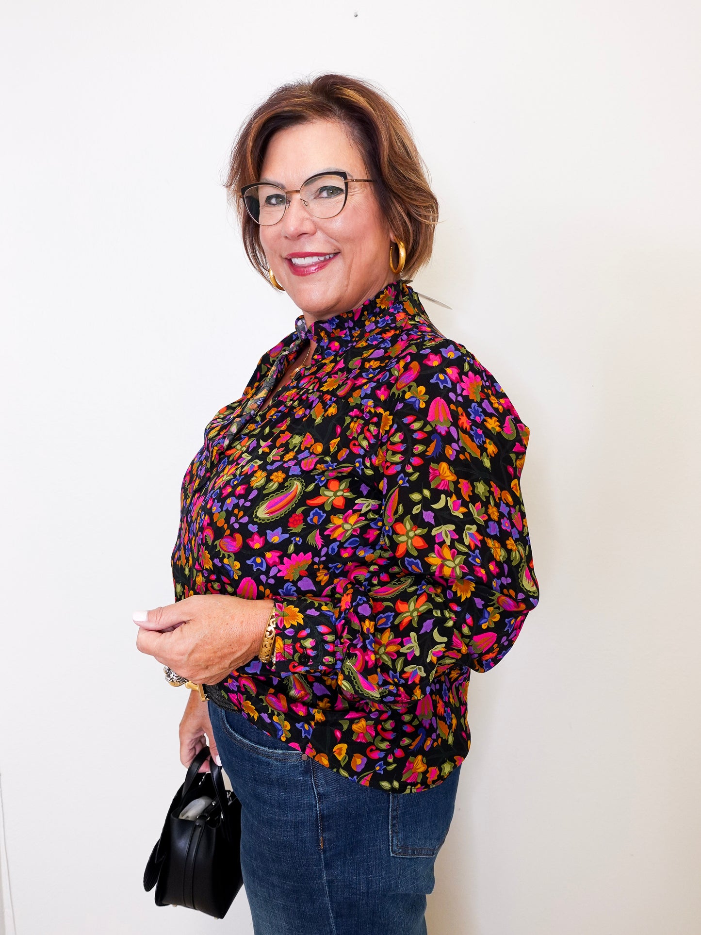 Woman wearing a colorful floral blouse against a white background