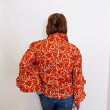 Person wearing a patterned orange and white shirt against a white background
