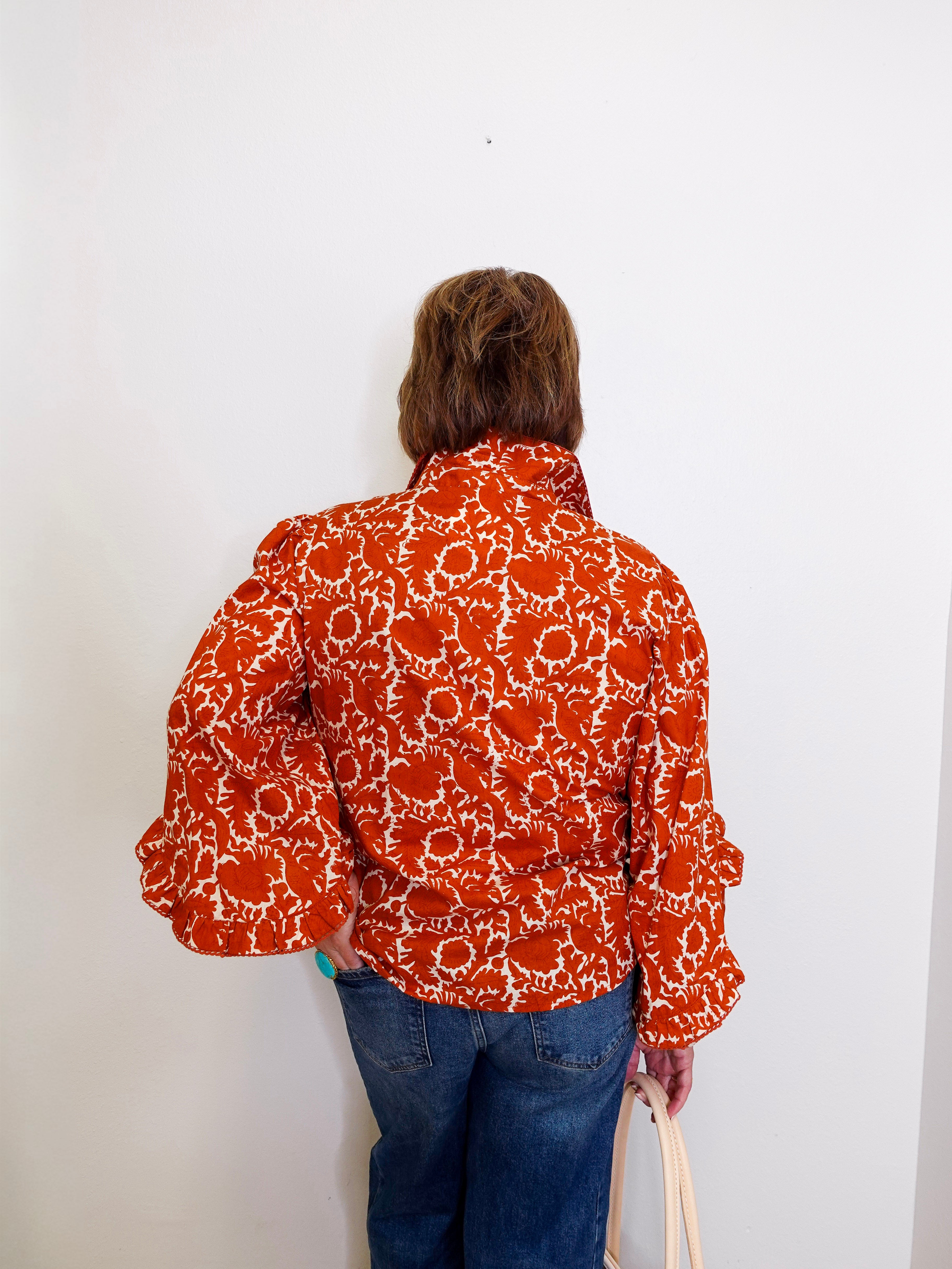 Person wearing a patterned orange and white shirt against a white background