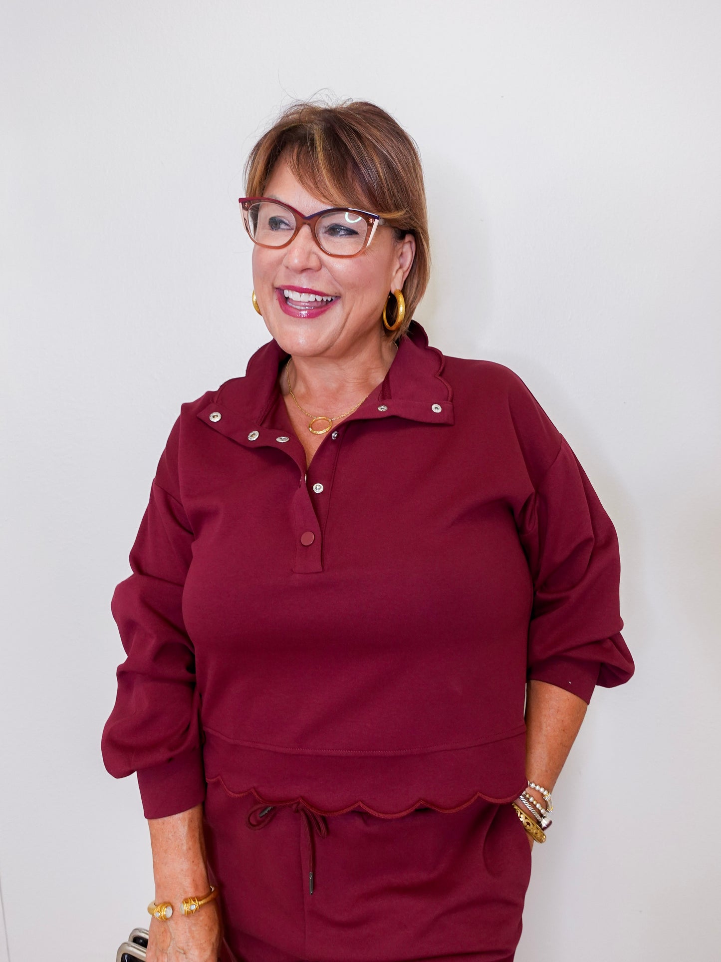 Woman wearing a burgundy outfit with glasses against a white background