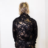 Person wearing a black floral-patterned jacket against a white background