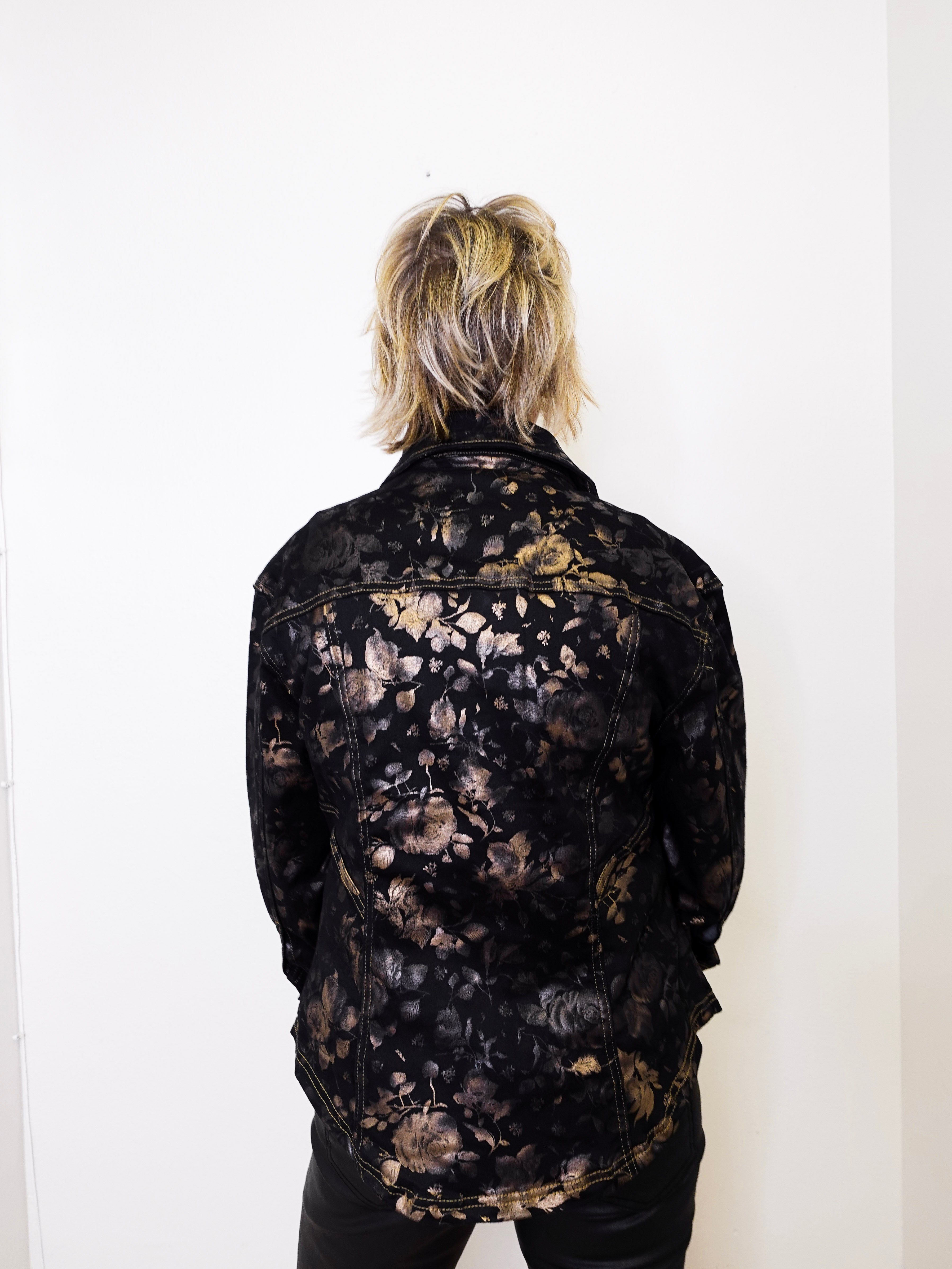Person wearing a black floral-patterned jacket against a white background