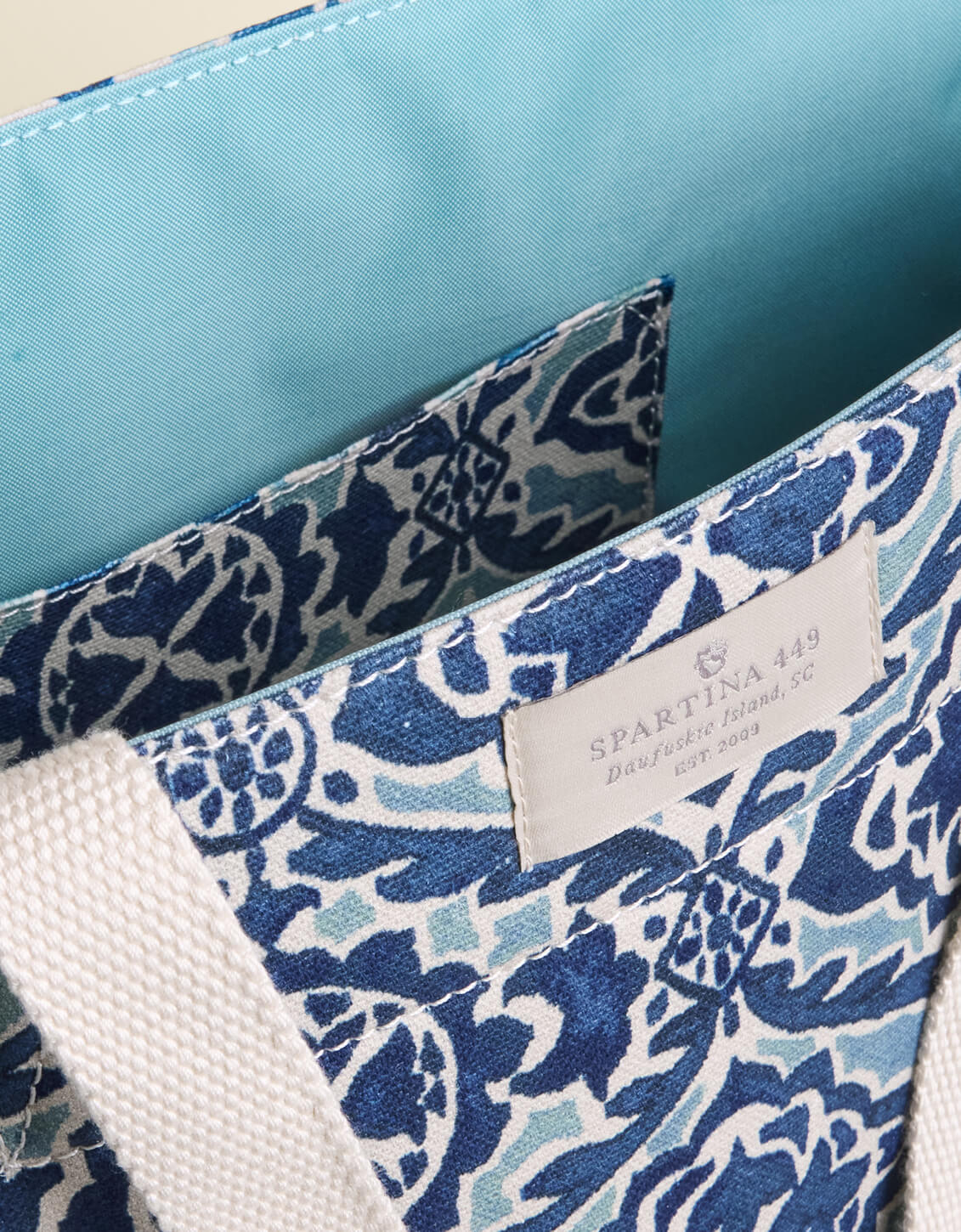Blue and white patterned bag with a Spartina 449 tag on a beige background