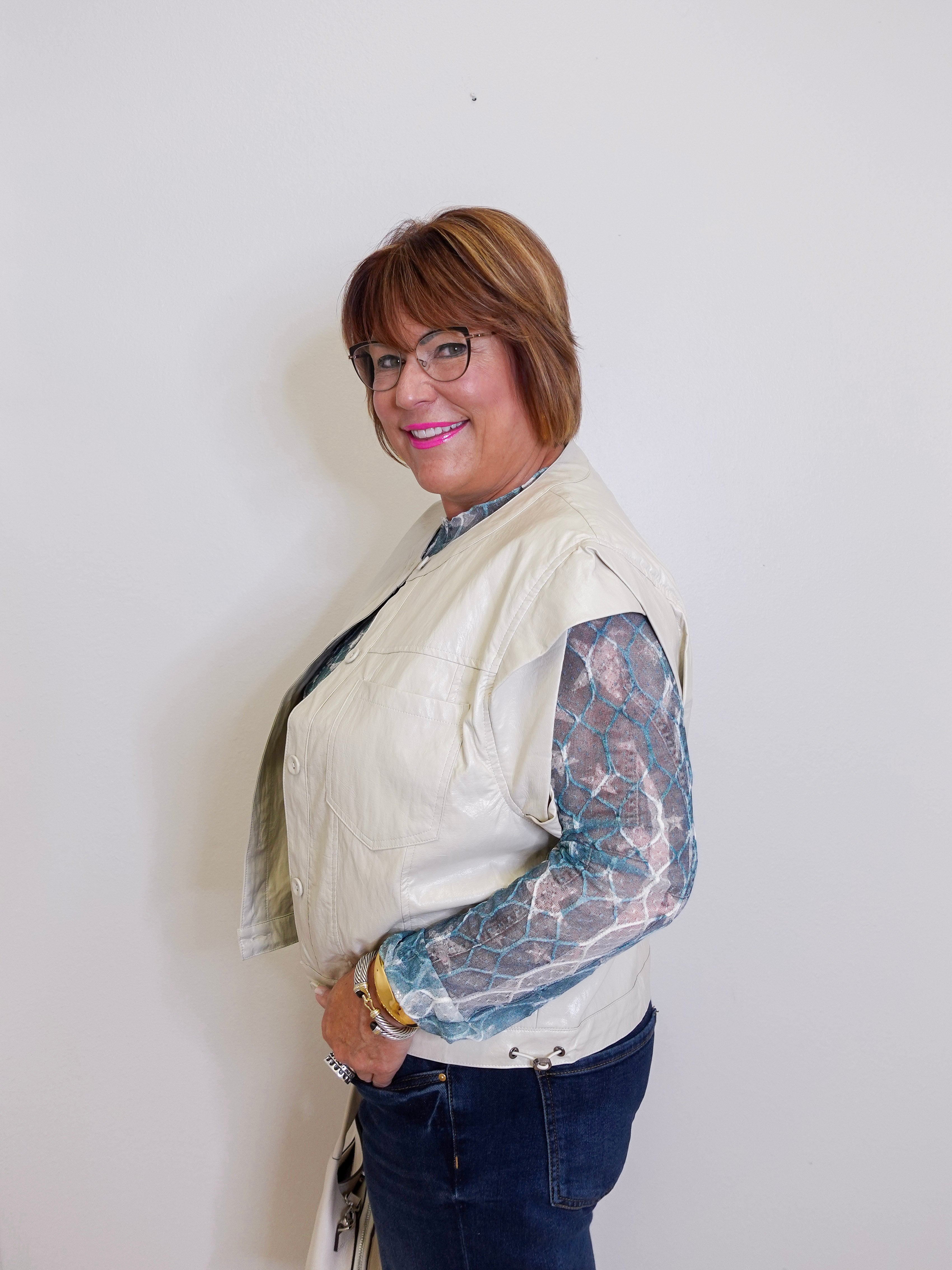 Person wearing a cream jacket with lace sleeves against a white background