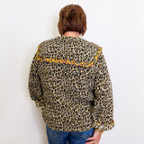 Person wearing a leopard print jacket with yellow accents on a white background