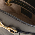 Close-up of a gray handbag with gold zipper and handle, featuring a brand logo.