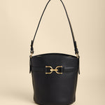 Black handbag with gold hardware on a beige background
