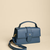 Blue handbag with a strap on a beige background
