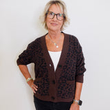Woman wearing a brown leopard print cardigan against a white background