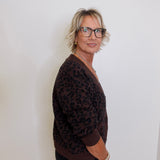 Person wearing a brown leopard print sweater against a white background