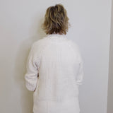 Person wearing a white textured sweater against a plain white background