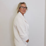 Person wearing a white sweater against a plain background
