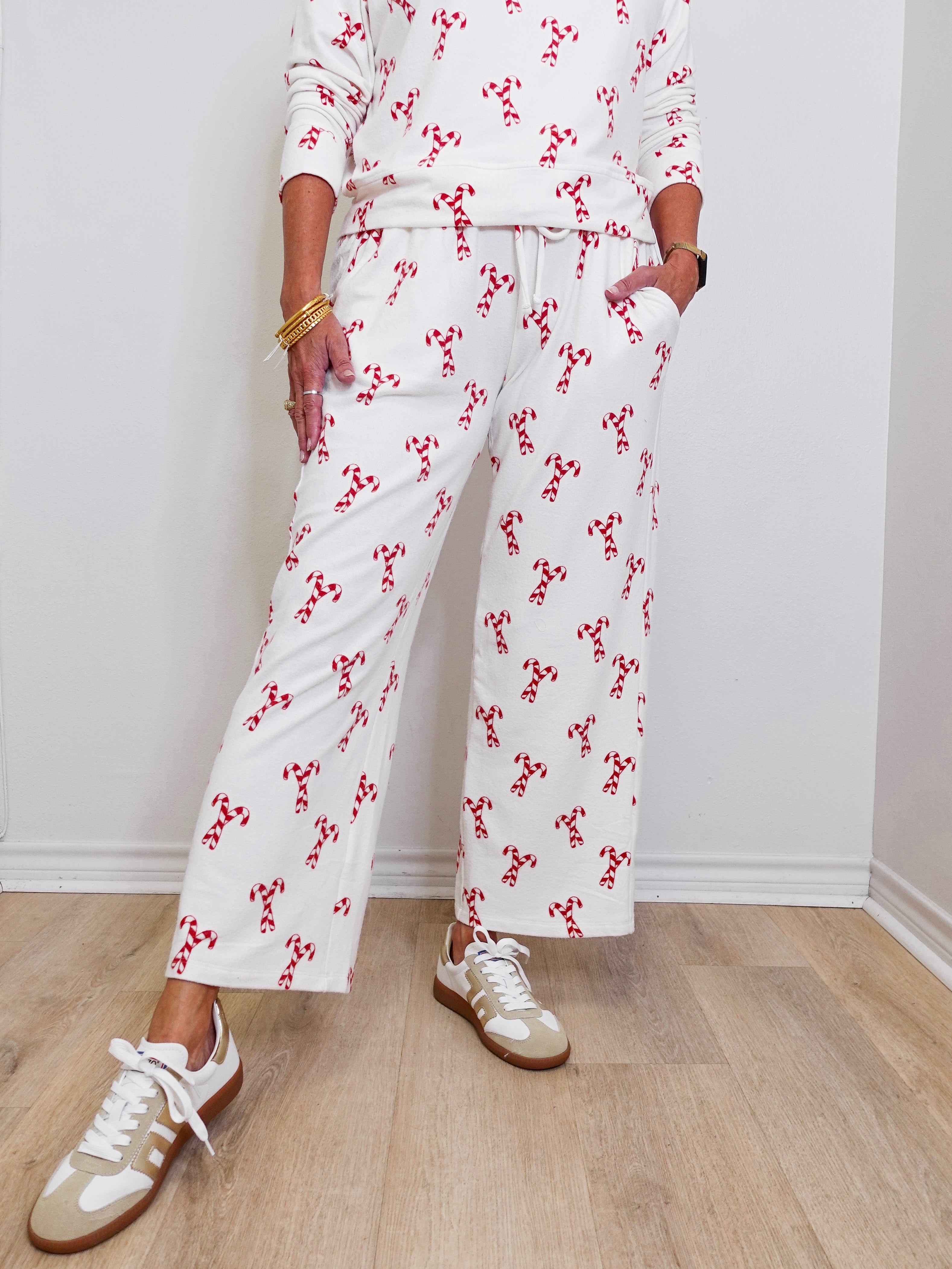 Person wearing a white outfit with red floral patterns on a wooden floor.