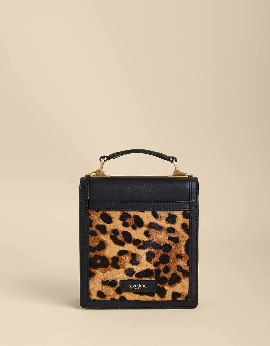 Small black handbag with a leopard print pocket on a beige background