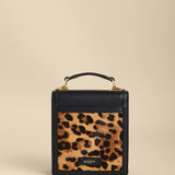 Small black handbag with a leopard print pocket on a beige background