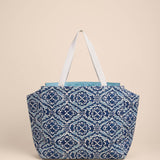 Blue patterned tote bag with white straps on a beige background