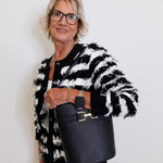 Woman holding a black handbag against a white background