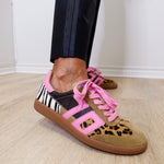 Sneakers with leopard print and zebra pattern on a wooden floor.
