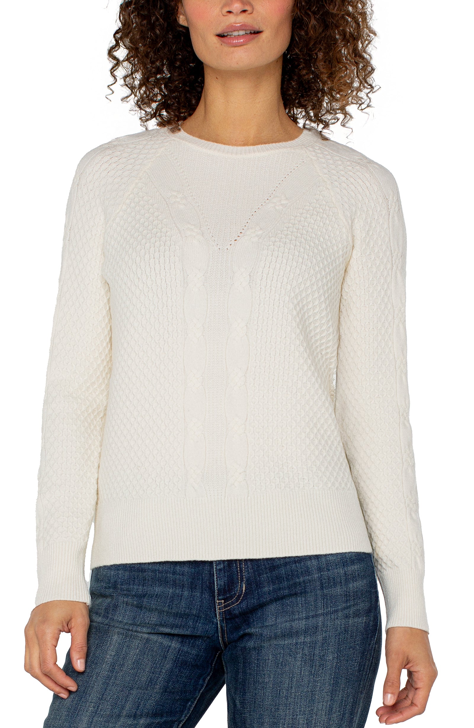 Woman wearing a white sweater and blue jeans on a white background