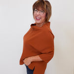Woman wearing a brown poncho against a white background