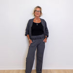Woman wearing a gray outfit standing against a white wall.