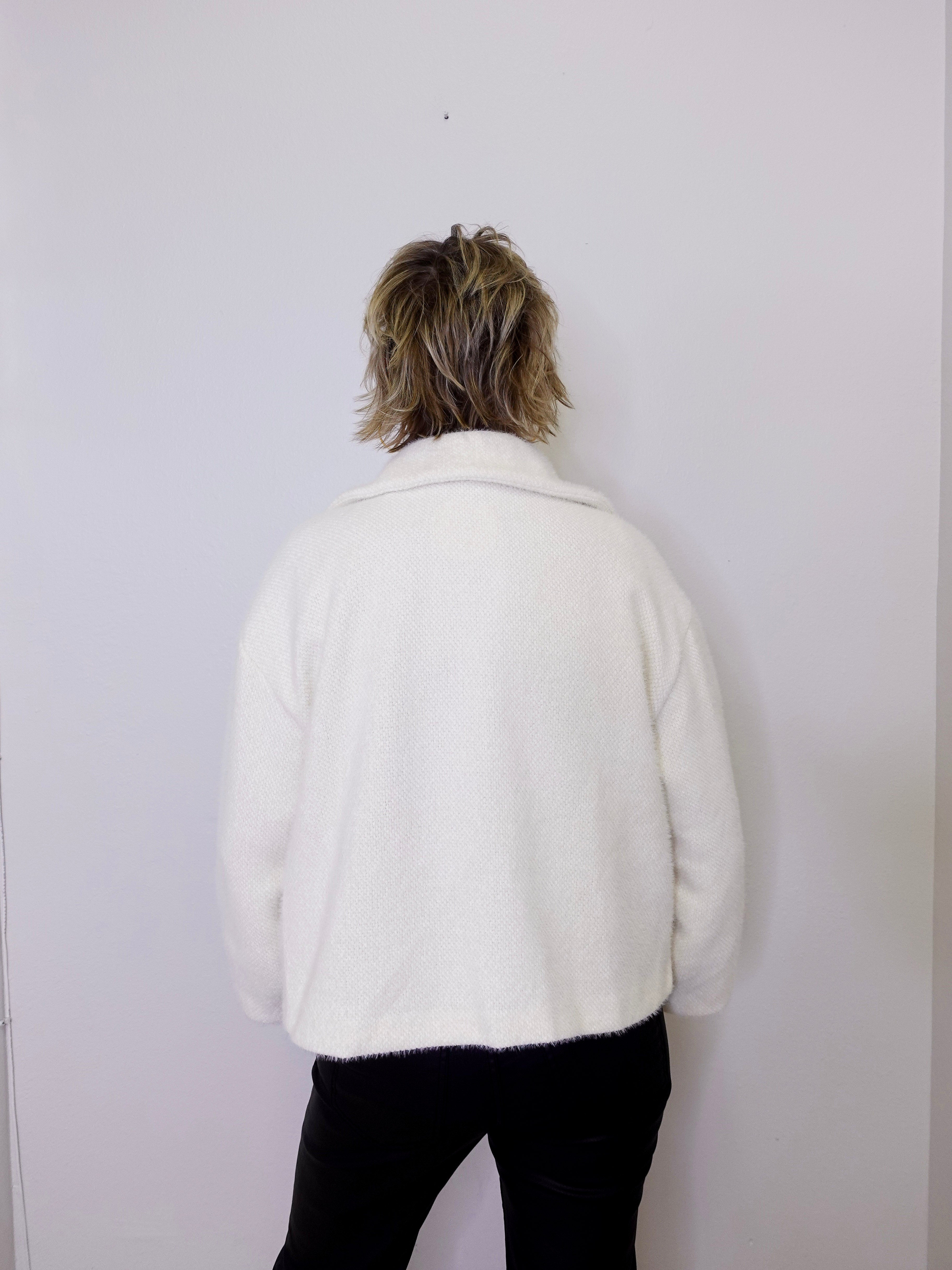 Person wearing a white jacket against a plain background