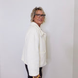 Person wearing a white coat against a plain background