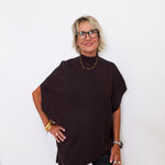 Woman wearing a dark brown poncho against a white background