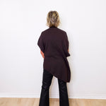 Person wearing a black outfit standing against a white wall.