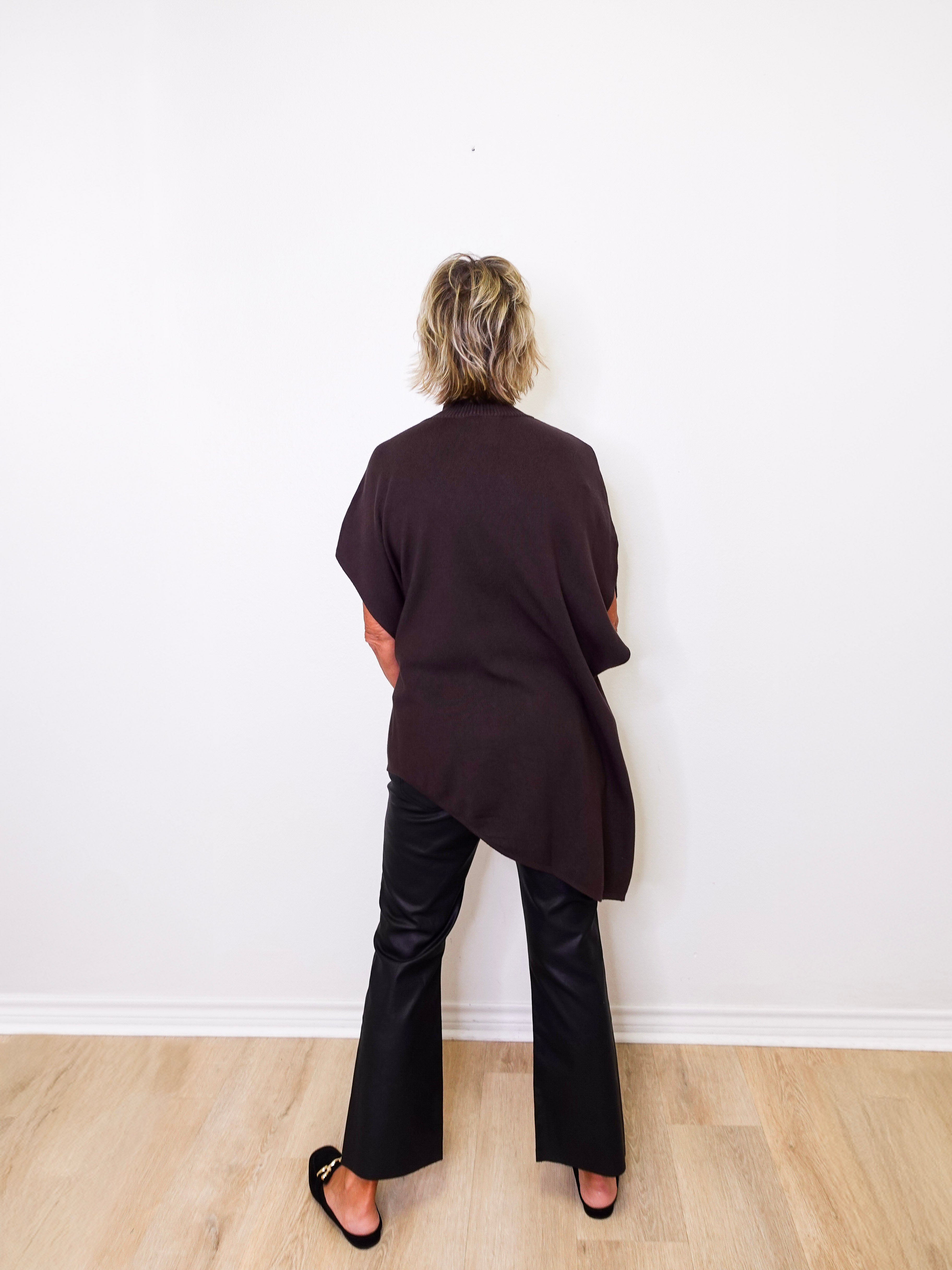 Person wearing a black outfit standing against a white wall.