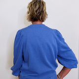 Person wearing a blue outfit against a white wall