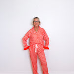 Person wearing a red and white striped pajama set against a white wall.