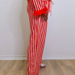 Person wearing red and white striped pajama set on a wooden floor.