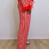 Person wearing red and white striped pajama set on a wooden floor.