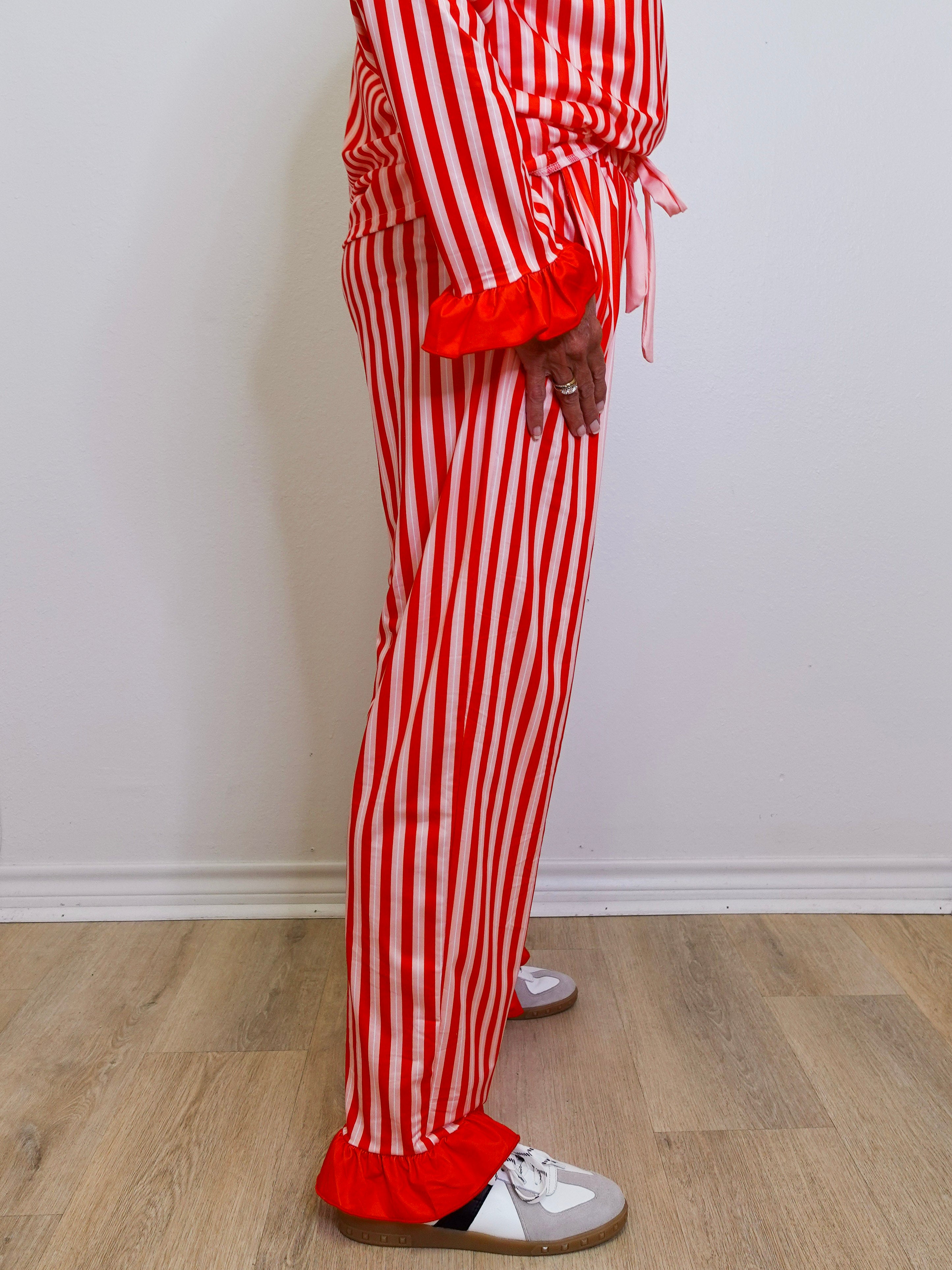 Person wearing red and white striped pajama set on a wooden floor.