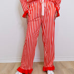 Person wearing a red and white striped outfit with ruffled pants on a light wooden floor.