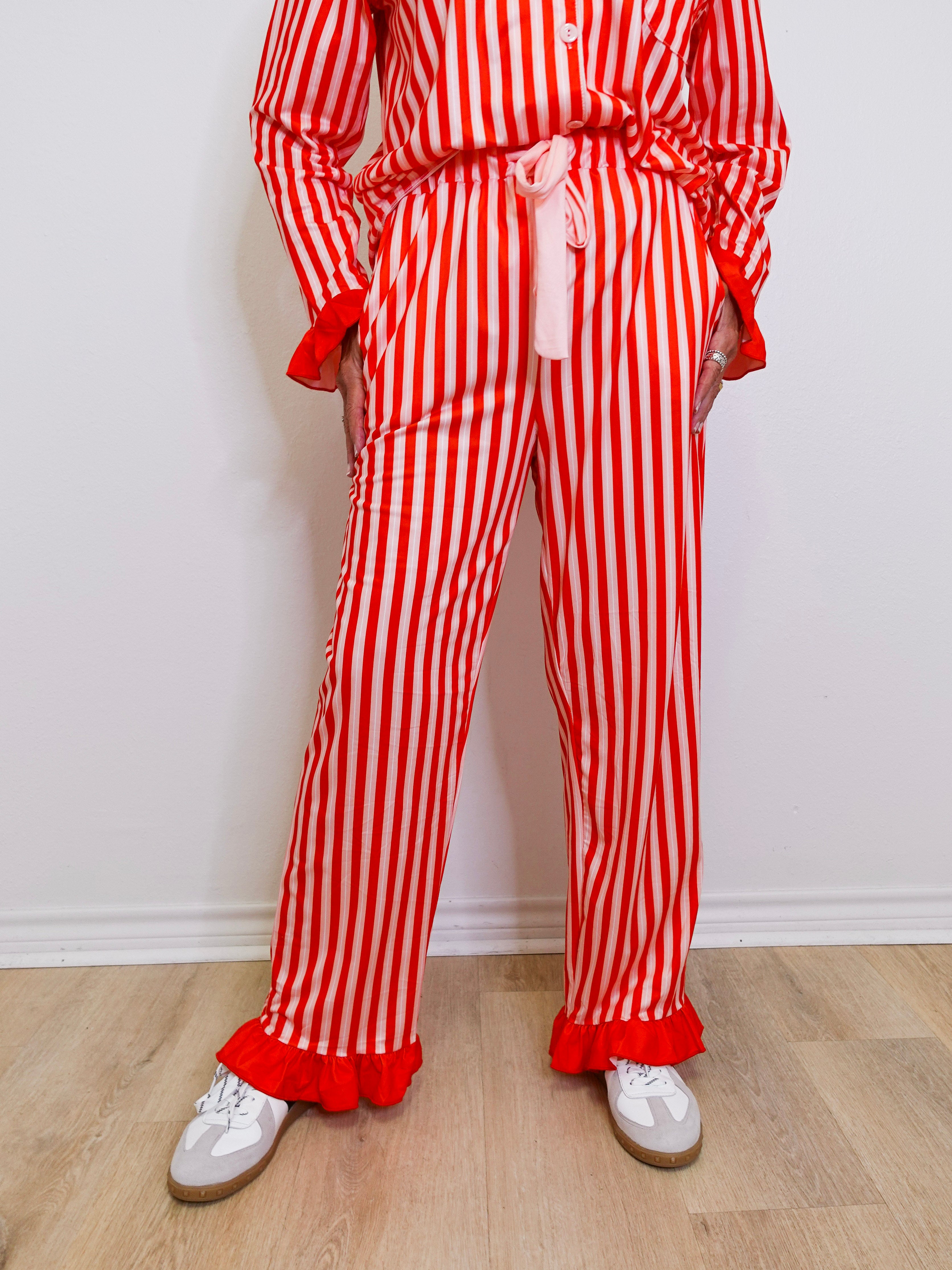 Person wearing a red and white striped outfit with ruffled pants on a light wooden floor.