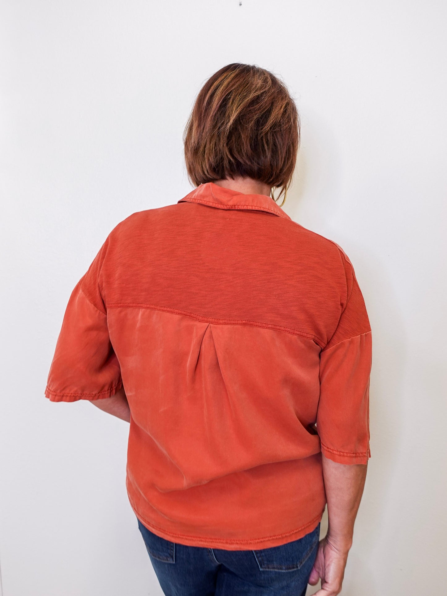 Person wearing a rust-colored shirt against a white background