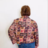 Person wearing a patterned jacket and blue jeans against a white background