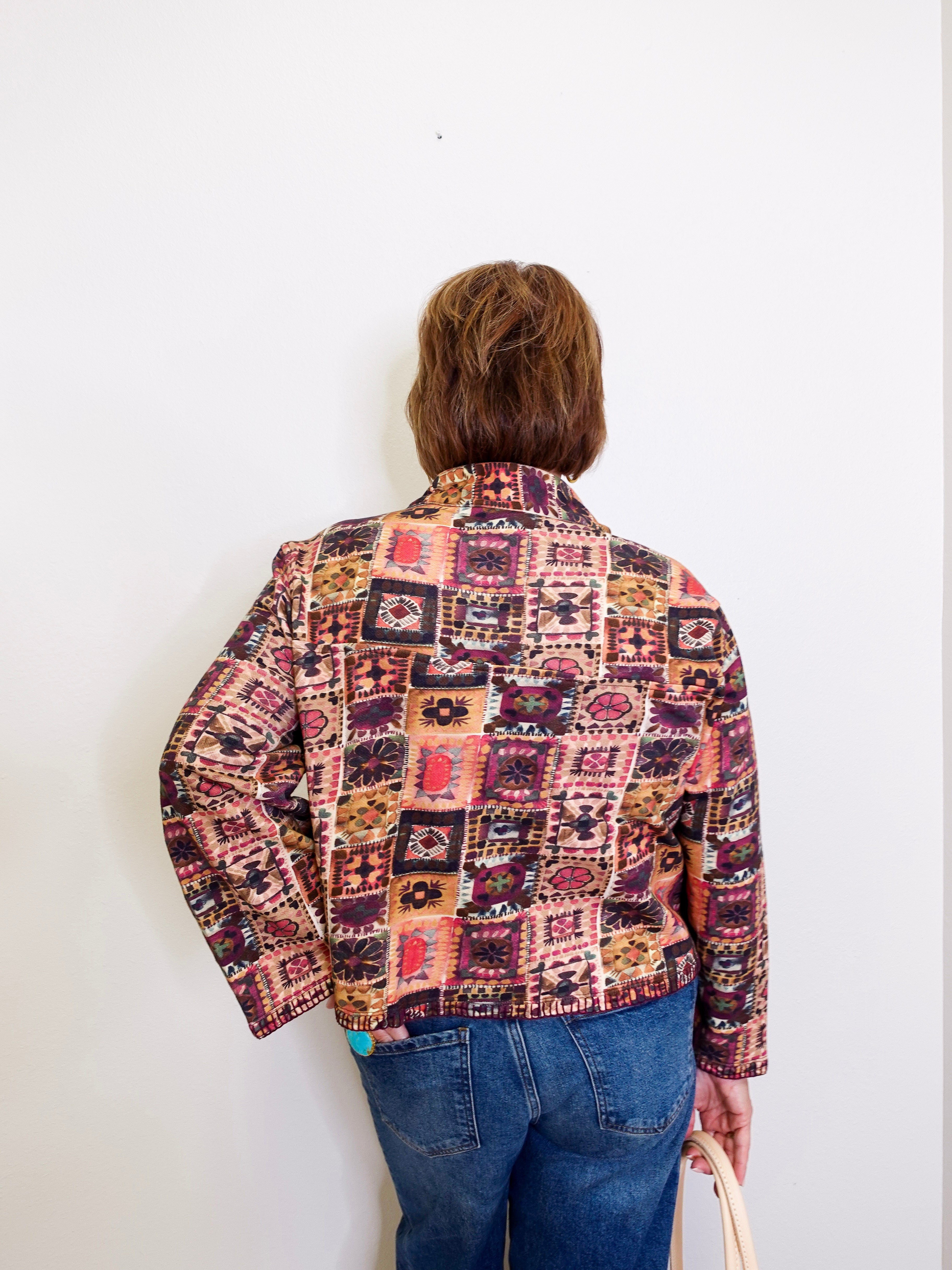 Person wearing a patterned jacket and blue jeans against a white background