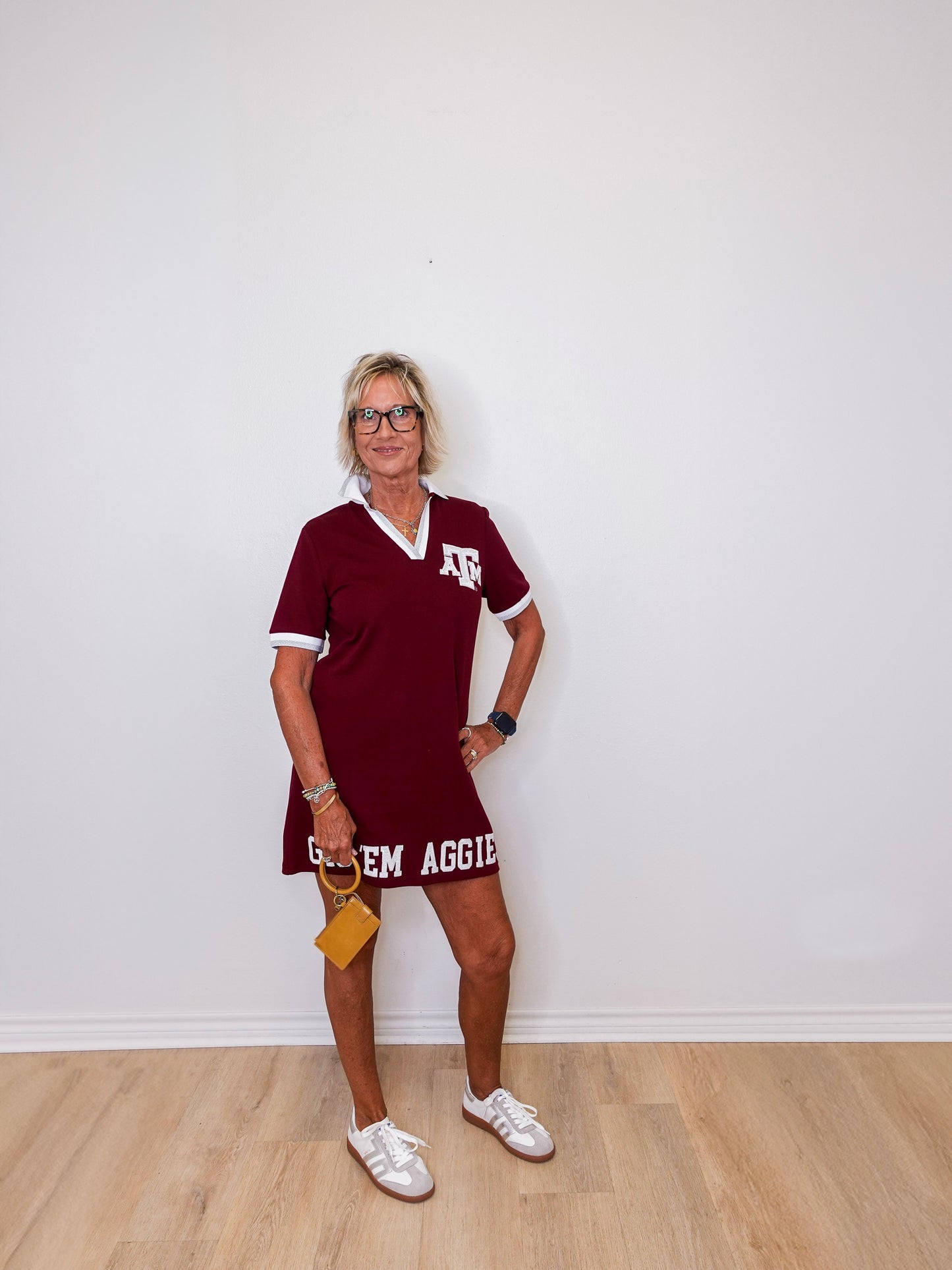 Woman wearing a maroon dress with 'Texas A&M' text against a white wall.