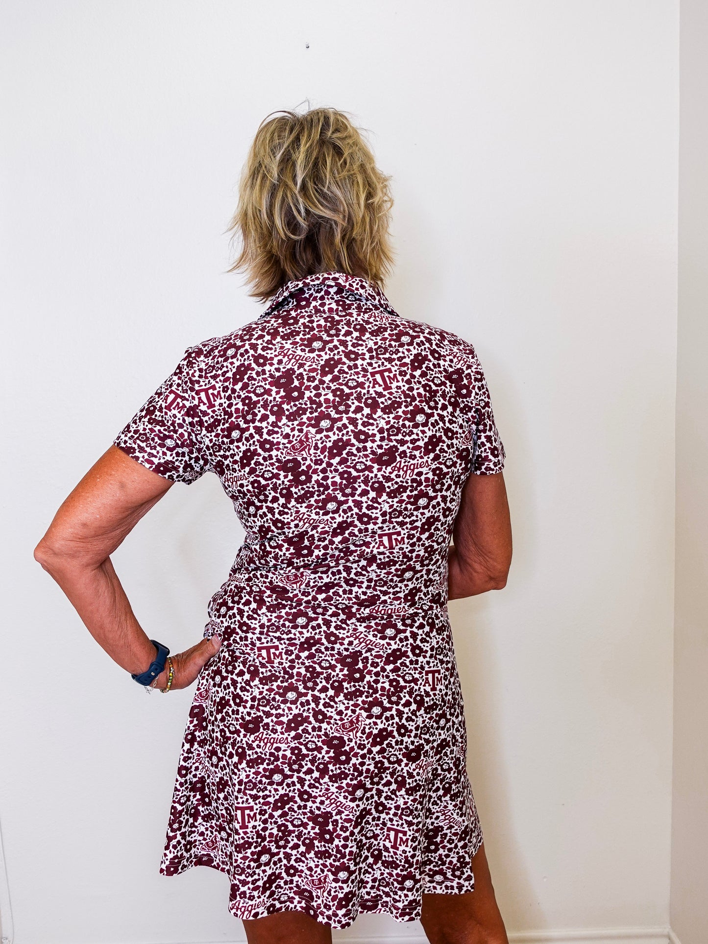 Person wearing a floral dress against a white wall