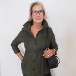 Woman wearing a green jacket and black pants against a white background