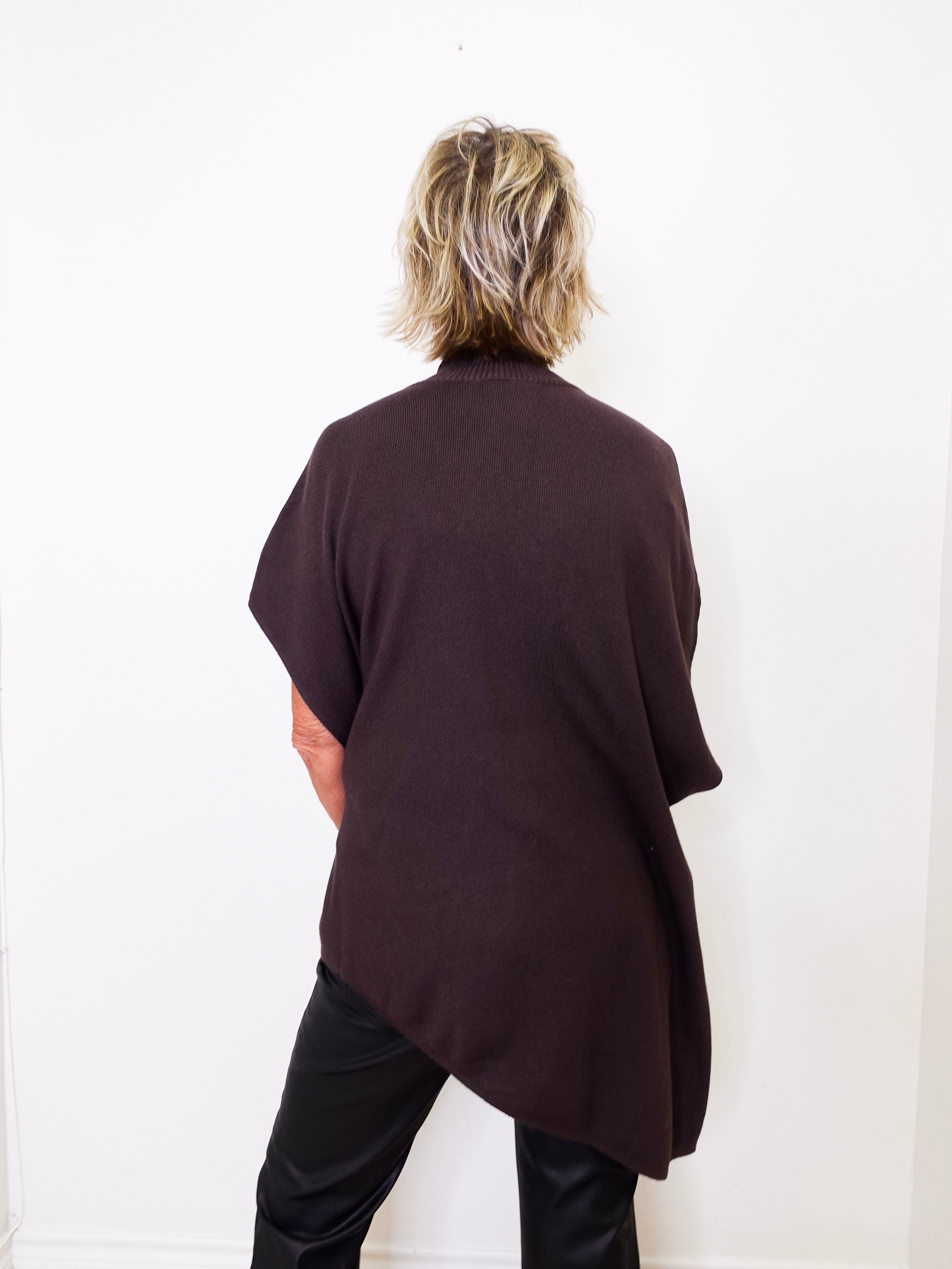 Person wearing a dark brown oversized sweater against a white background