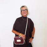 Woman holding a brown handbag against a white background