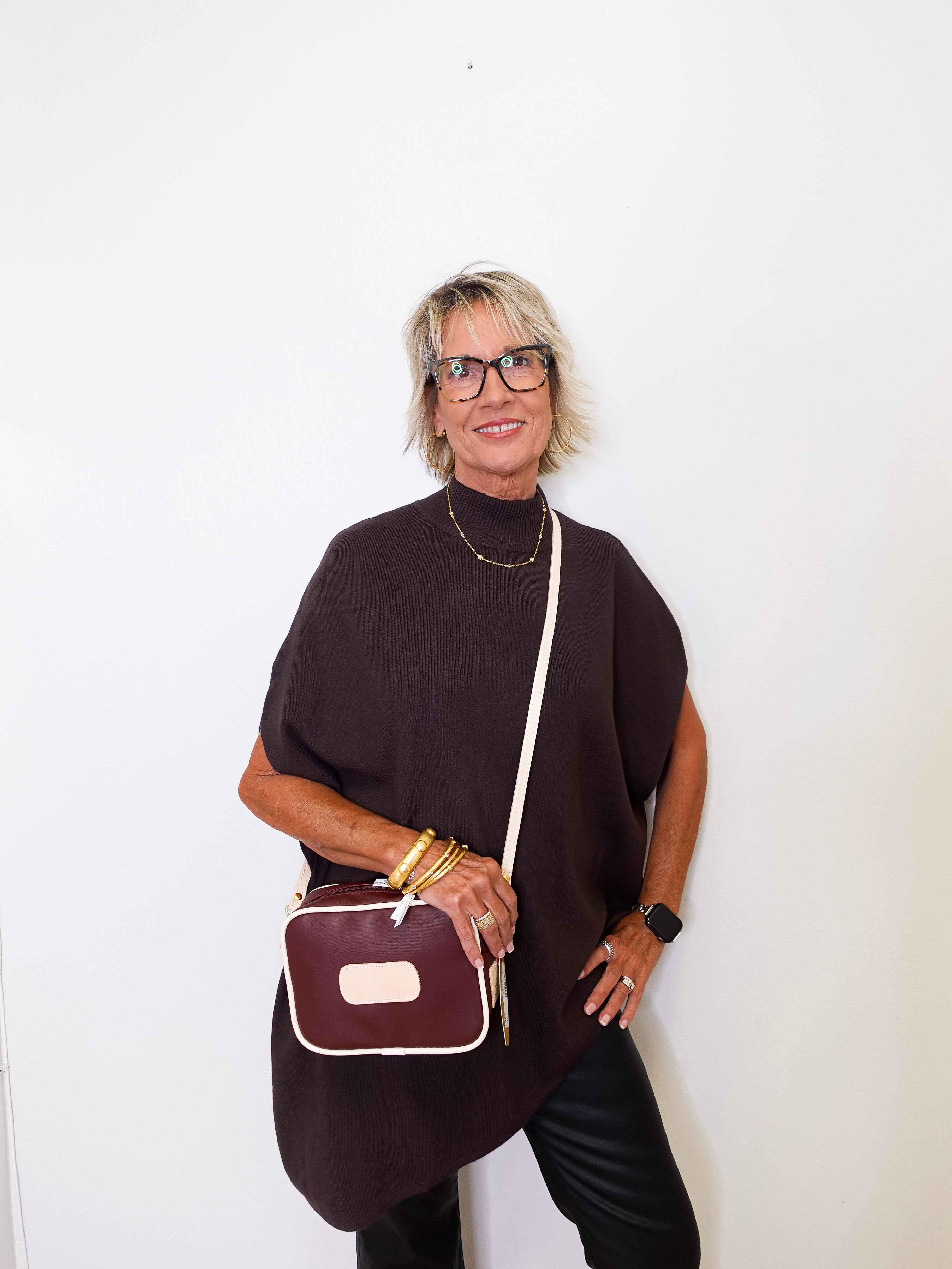 Woman holding a brown handbag against a white background