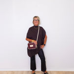 Woman holding a crossbody bag against a white wall