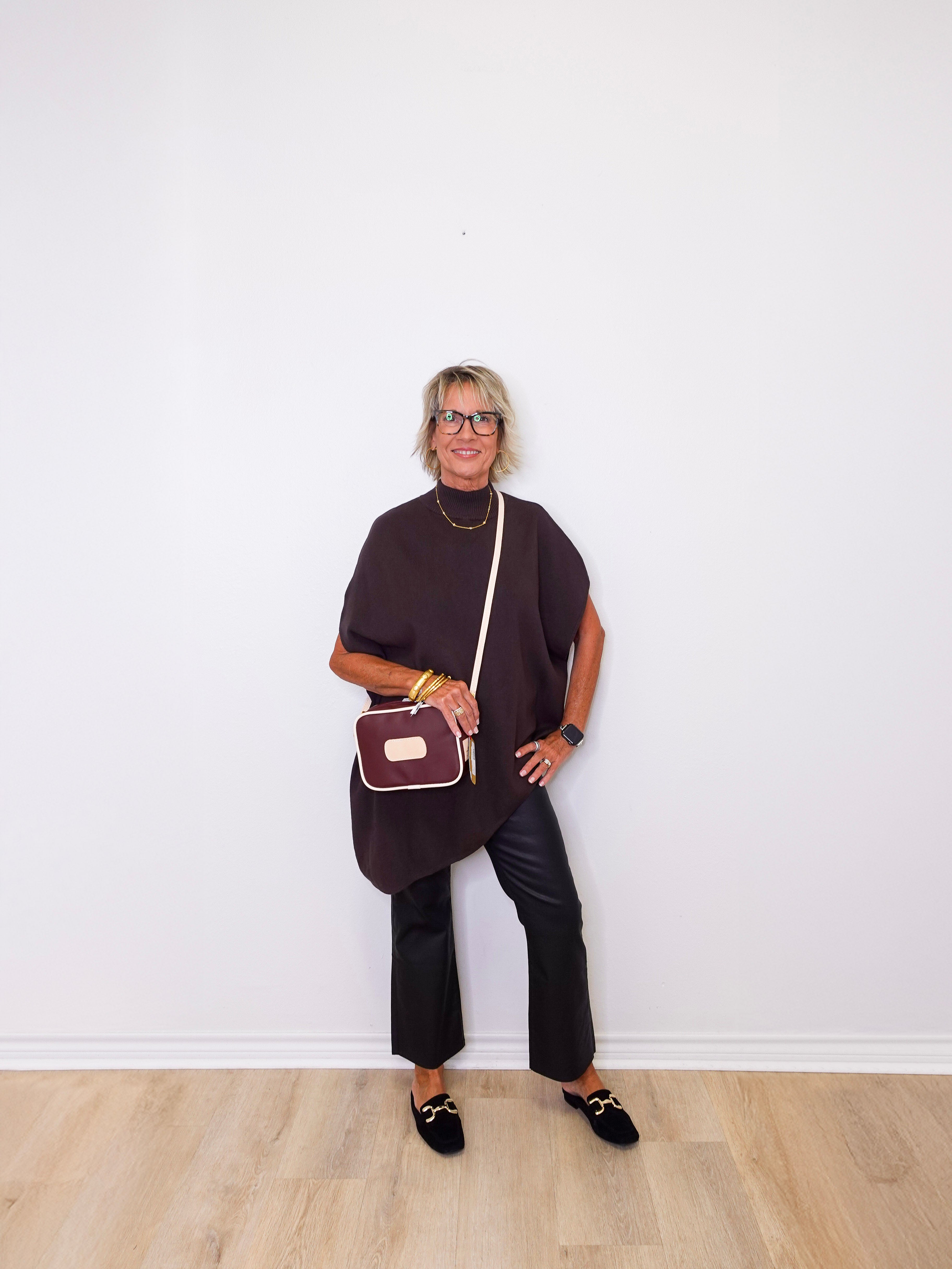 Woman holding a crossbody bag against a white wall