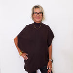 Woman wearing a dark brown poncho against a white background